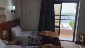 Ein Hotelzimmer mit zwei Betten, einem Balkon mit Geländer und Blick ins Freie.