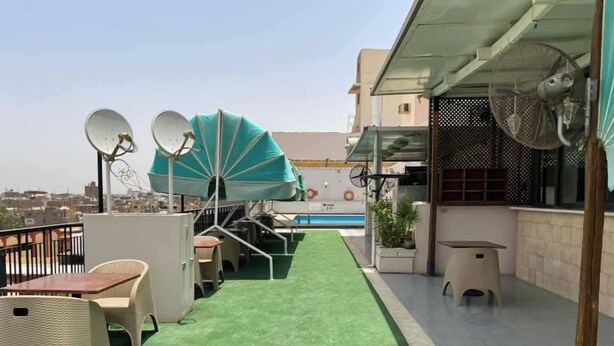 Eine Dachterrasse mit Kunstrasen, Gartenmöbeln, Satellitenschüsseln und einem Pool.