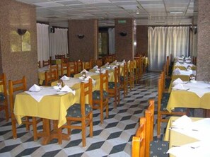 A dining area with tables and chairs, checkered floor, and a brick wall. - Stjosephhotel (Luxor)