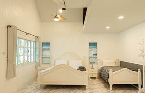 Une chambre avec deux lits, un ventilateur de plafond et une fenêtre avec des rideaux.