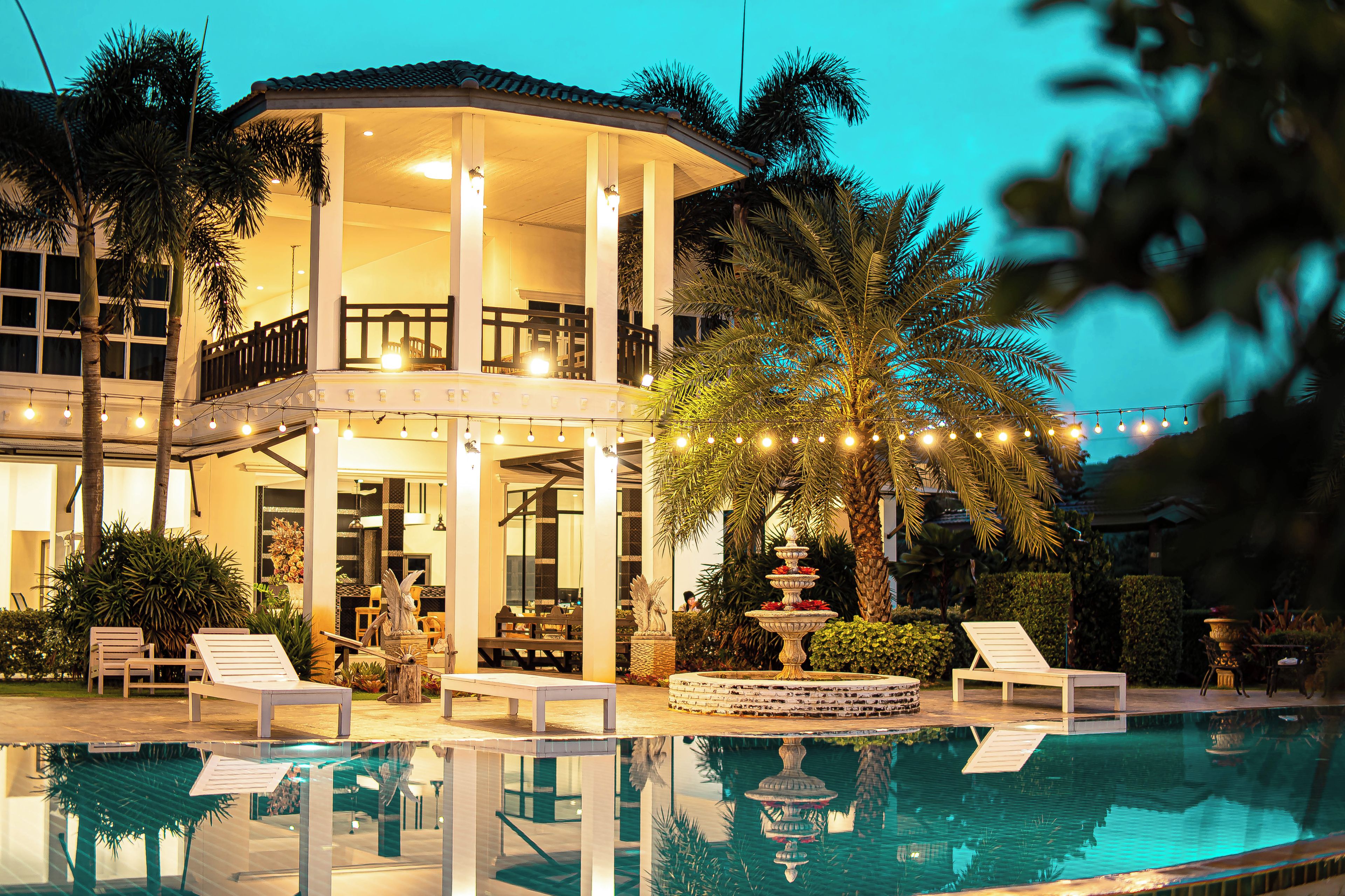A poolside area with lounge chairs, a fountain, and a covered seating area.