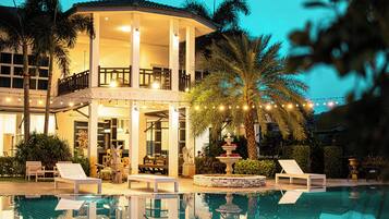 A poolside area with lounge chairs, a fountain, and a covered seating area.