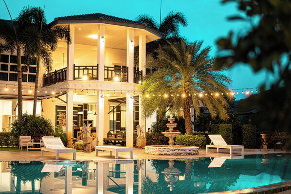 A poolside area with lounge chairs, a fountain, and a covered seating area.