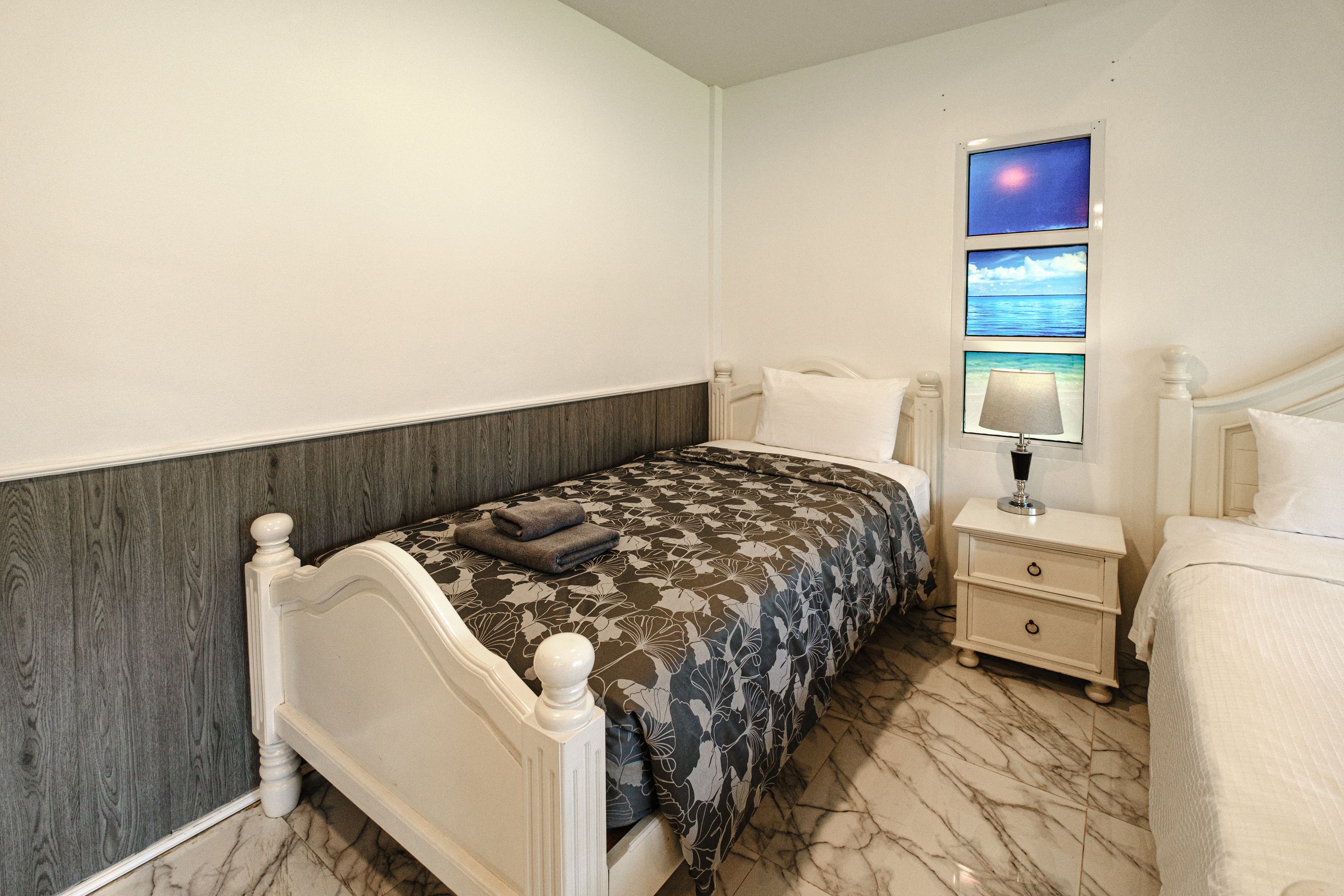 A bedroom with a bed, a nightstand, a lamp, and a wall-mounted TV.