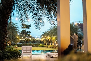A poolside area with a bench, palm trees, and string lights.