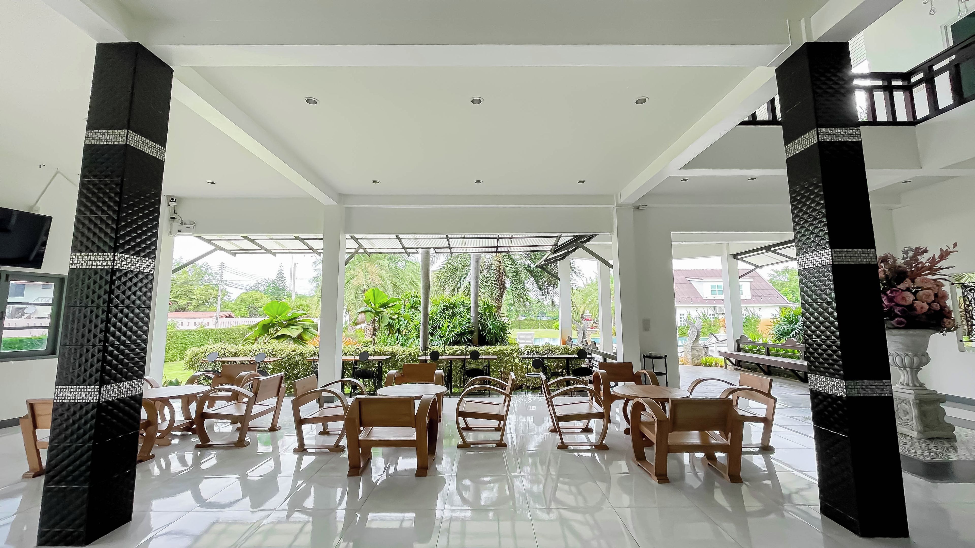 A spacious indoor area with a high ceiling, large windows, and a view of greenery outside.