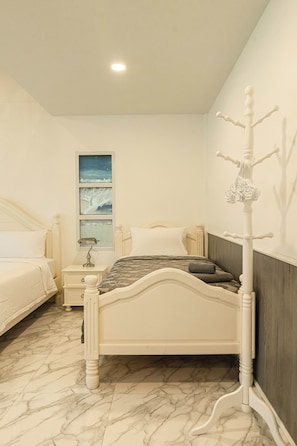 Un dormitorio con cama, mesita de noche, lámpara y perchero en la pared.
