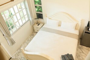 Ein ordentlich eingerichtetes Schlafzimmer mit einem Bett, Nachttischen und einem Fenster mit Vorhängen.