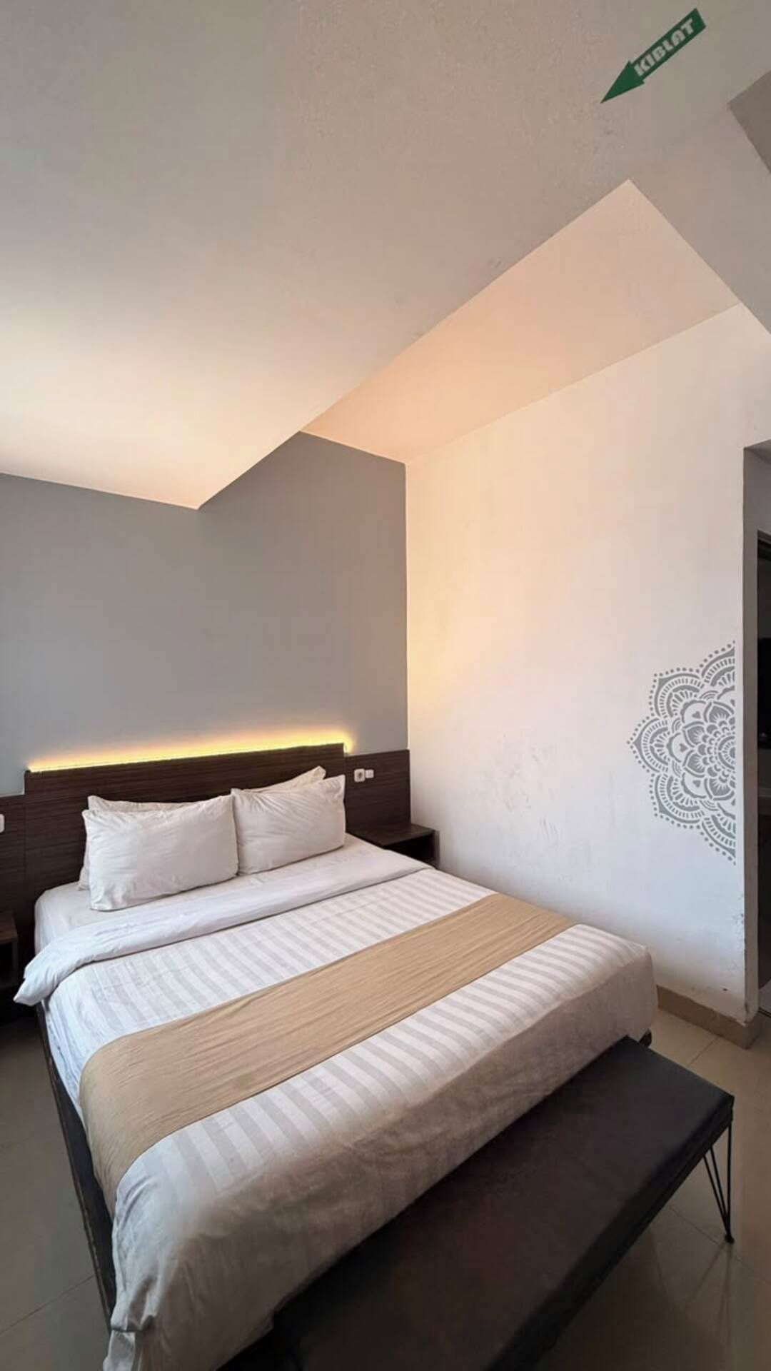 Una habitación de hotel moderna con cama, mesita de noche y un diseño decorativo en la pared.