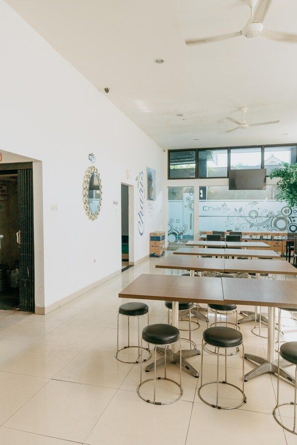 Una habitación amplia con una mesa larga, varias sillas, un ventilador de techo y un gran ventanal con vistas.
