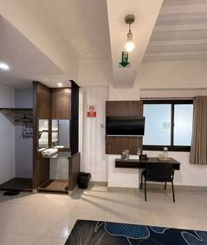 A modern living room with a flat-screen TV, a dining area with a table and chairs, a built-in bench, and a large window with curtains.