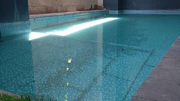 A swimming pool with a tiled edge, surrounded by walls with a textured pattern.