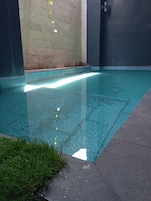 Una piscina con borde de azulejos, rodeada de muros con un diseño texturizado.
