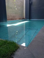 Una piscina con borde de azulejos, rodeada de muros con un diseño texturizado.