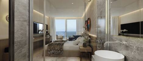 Un baño moderno con una bañera grande, ducha con mampara de vidrio y vistas al mar.