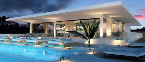 Un área moderna junto a la piscina con sillones de descanso, una piscina y una zona de estar cubierta.