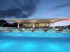 Un hotel moderno con zona de piscina, mobiliario exterior y un espacio lounge cubierto.