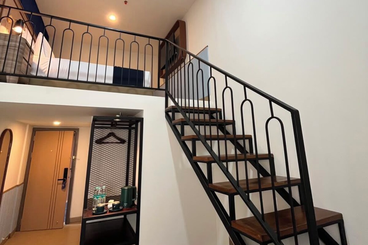 Eine Treppe mit Metallgeländer, die zu einem Balkon im zweiten Stock führt.