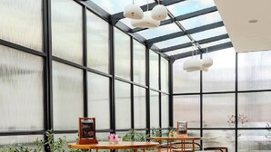 A spacious indoor area with a high ceiling and large windows, featuring multiple tables and chairs arranged for seating. - Du Palais Hotel (Jambi)