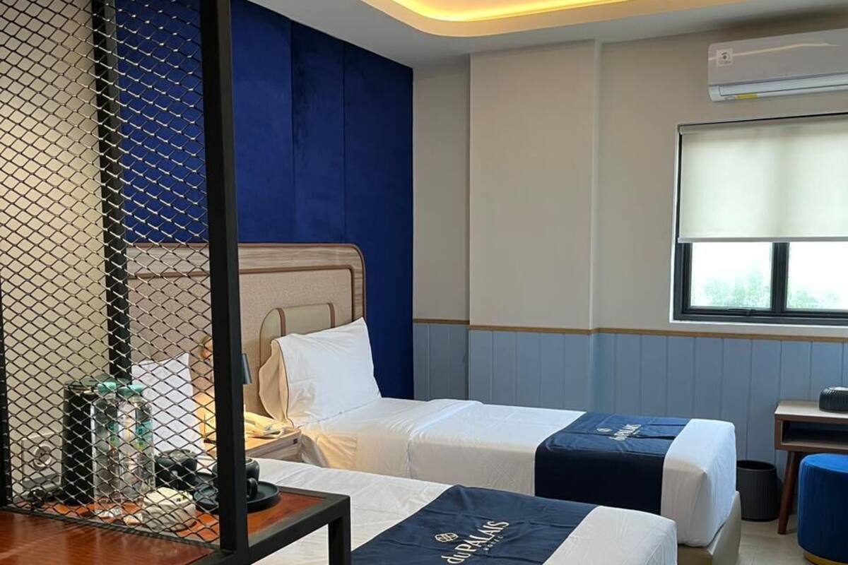 Une chambre d’hôtel avec deux lits, un bureau et une fenêtre.