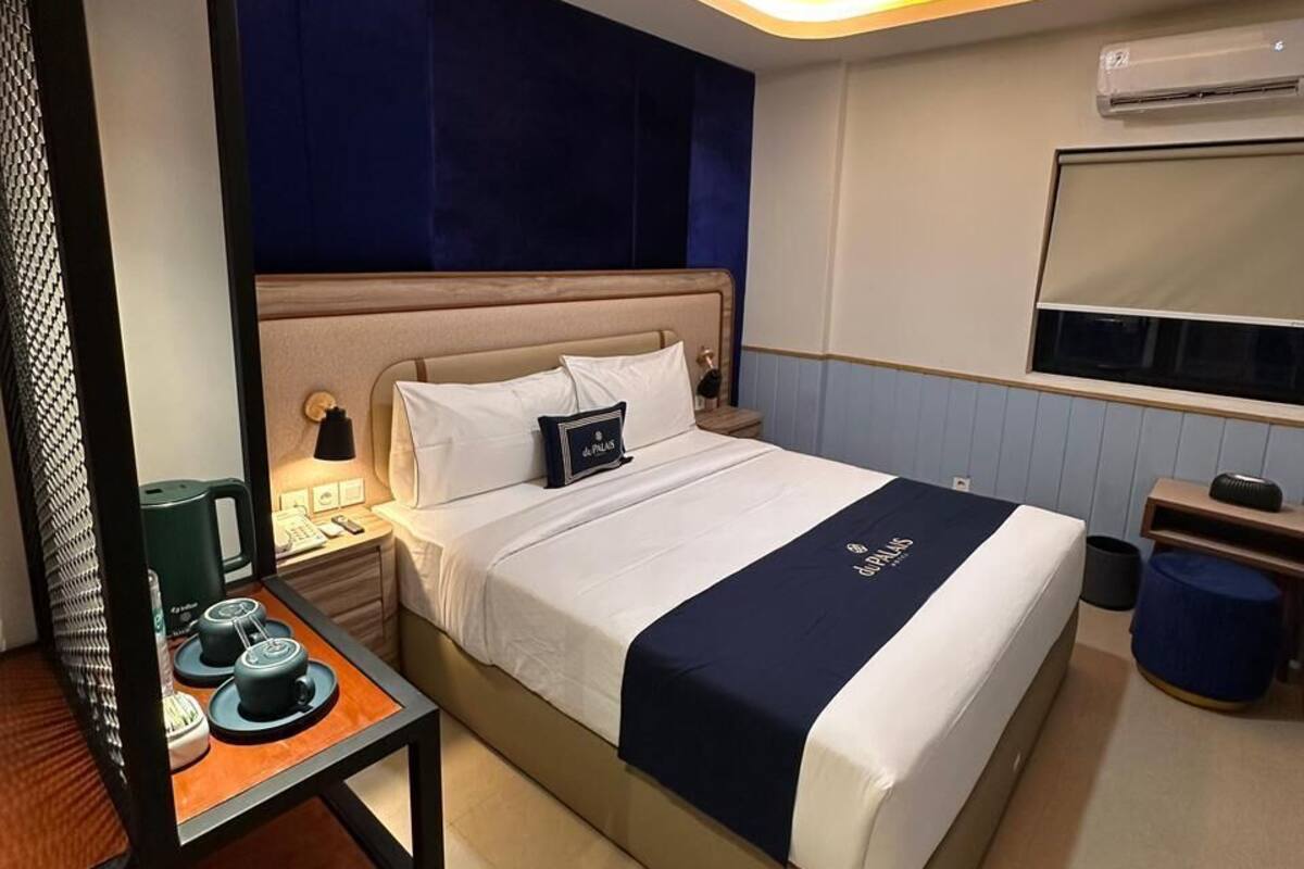 Une chambre d’hôtel avec un lit, une table de chevet, une lampe et un miroir.