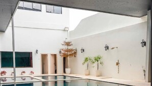 A modern indoor swimming pool with clear water, surrounded by white walls and potted plants. - Du Palais Hotel (Jambi)