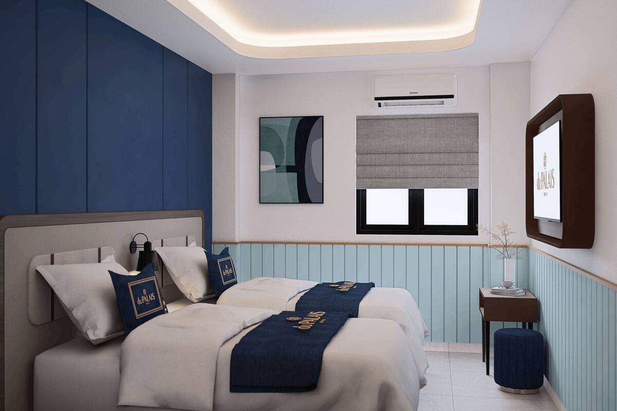 A hotel room with two beds, a bedside table, a small stool, a window with blinds, an air conditioning unit, and a framed picture on the wall.