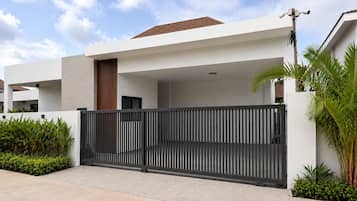 Um edifício moderno com entrada fechada, telhado plano e caminho de concreto.