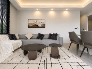 A modern living room with a sofa, two coffee tables, and a painting on the wall. - Villa Luna 2BR Private Plunge Pool (Si Sunthon)