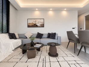 Ein modernes Wohnzimmer mit einer Couch, zwei Couchtischen und einem Sessel.