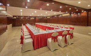 A conference room with a long table, white chairs with red sashes, and wooden paneling on the walls. - Tulip Inn Koramangala Bangalore (Bengaluru)