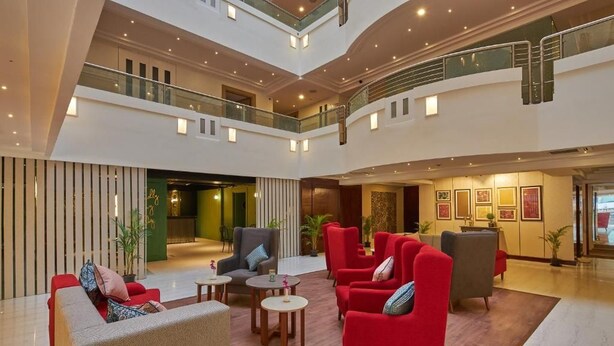 Um hall amplo com várias áreas de estar, escadaria e balcão de recepção.