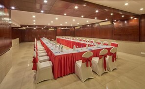 A conference room with a long table, white chairs with red sashes, and wooden paneling on the walls. - Tulip Inn Koramangala Bangalore (Bengaluru)