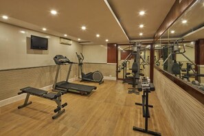 Une salle de sport équipée de tapis de course, de vélos elliptiques et de matériel de musculation.