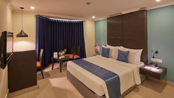 A hotel room with a bed, a desk, a chair, a TV, and a nightstand.