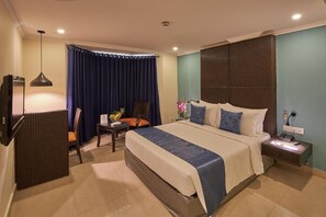 A hotel room with a bed, a desk, a chair, a TV, and a nightstand. - Tulip Inn Koramangala Bangalore (Bengaluru)