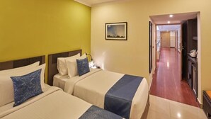 Habitación de hotel con dos camas, un pasillo y una puerta que da a una zona de cocina.