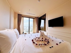 A hotel room with a large bed, a flat-screen TV mounted on the wall, and a window with curtains. - Peace Home Boutique Hotel Phan Thit (Phu Thuy)