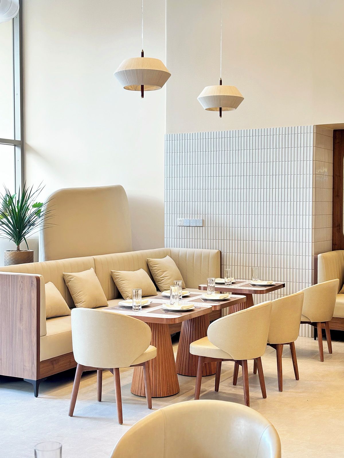 A modern interior with a sofa, dining tables, chairs, and pendant lighting.