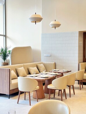 A modern interior with a sofa, dining tables, chairs, and pendant lighting. - Peace Home Boutique Hotel Phan Thit (Phu Thuy)