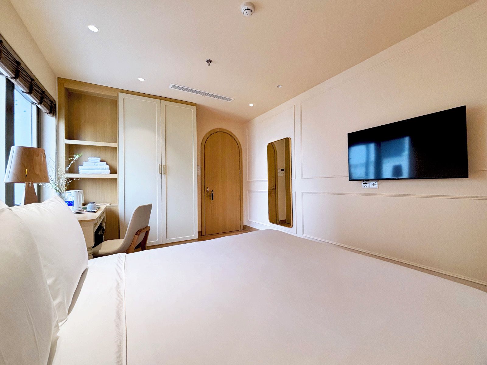 Une chambre d’hôtel comprenant un lit, un bureau, une armoire, une télévision et un miroir.