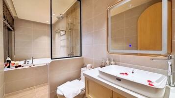 Ein modernes Badezimmer mit Badewanne, Waschbecken, Toilette und einem großen Spiegel.