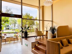 Een modern interieur met een zithoek, een trap en grote ramen met uitzicht op het omliggende landschap.