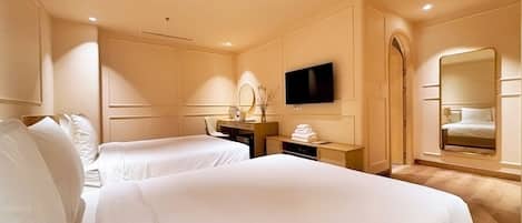 Une chambre d’hôtel avec deux lits, un bureau, une télévision, un miroir et un miroir dans la salle de bain.