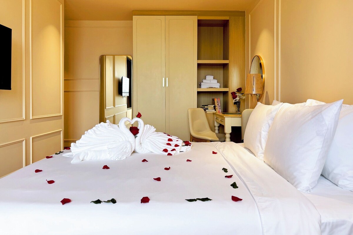 Ein Hotelzimmer mit Bett, Schreibtisch, Stuhl, Kleiderschrank und Spiegel.