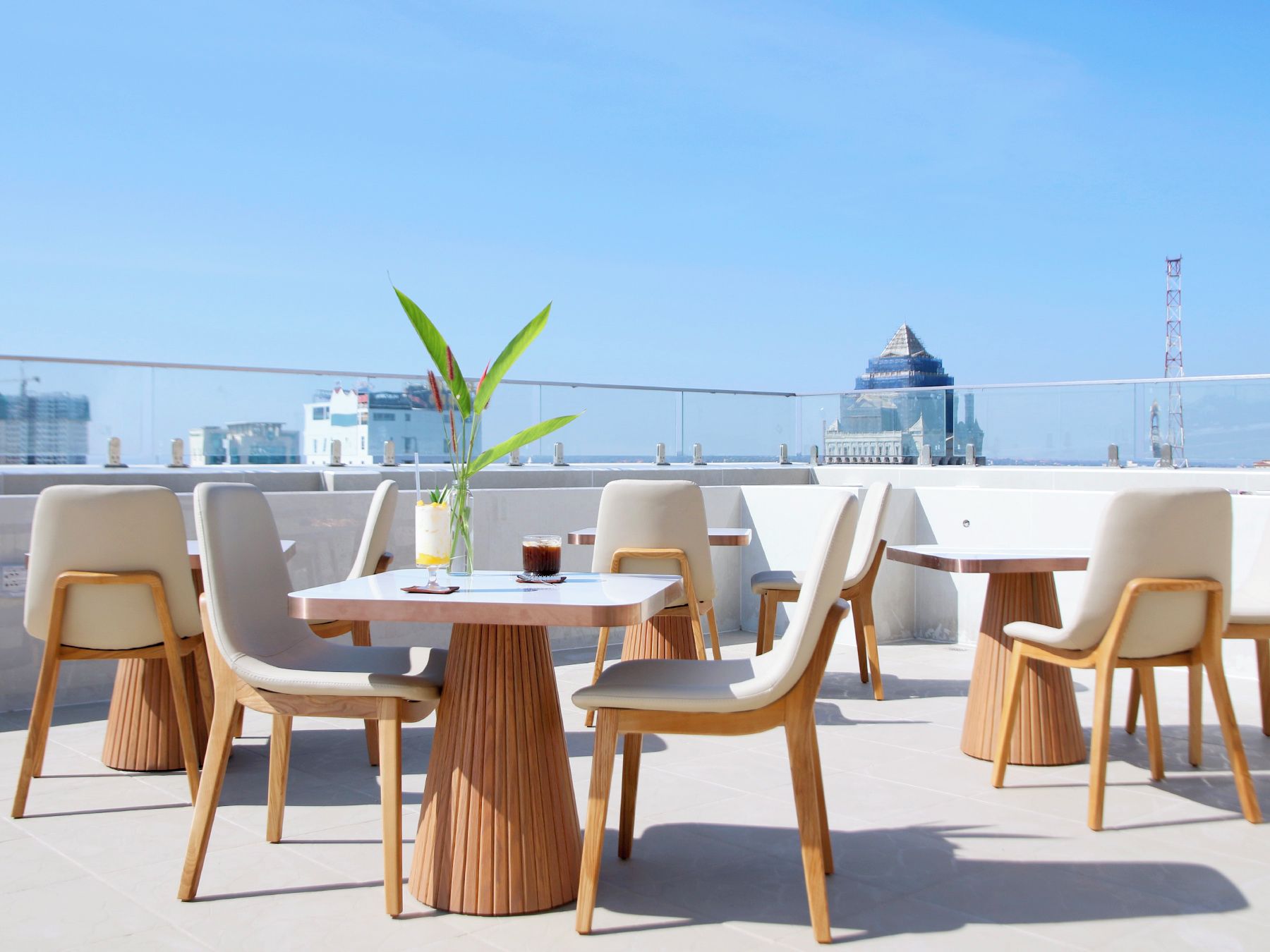 Une terrasse sur le toit, avec des tables et des chaises, un pot de fleurs et une vue sur le paysage urbain.