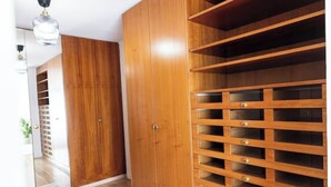 A wooden wardrobe with multiple drawers and shelves, a mirror, and a ceiling light. - Elite Villa Geneva (Cologny)