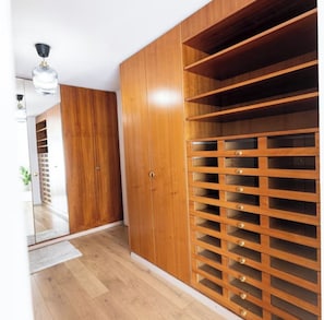 Ein Holzkleiderschrank mit mehreren Schubladen und Ablagen, einem Spiegel und einer Deckenleuchte.