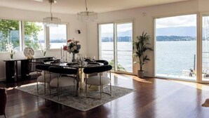 A spacious dining area with a view of a lake, a chandelier, and a large window.