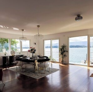 A spacious dining area with a view of a lake, a chandelier, and a large window.